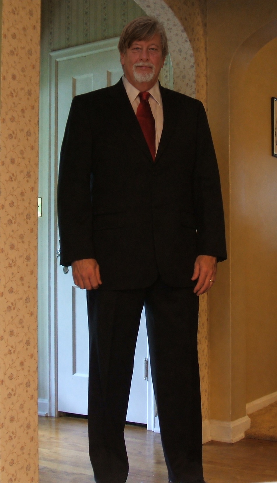 Richard wearing a dark suit and red tie